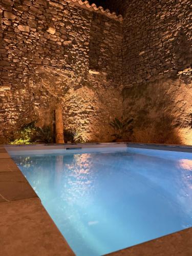 a large swimming pool with blue lighting in a stone wall at La Maison du Puits in Cesseras