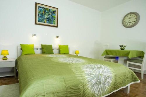 sypialnia z zielonym łóżkiem i zegarem na ścianie w obiekcie Green Place w Splicie