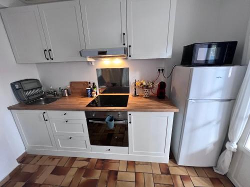 une cuisine avec des armoires blanches et un réfrigérateur blanc dans l'établissement Sympathique studio en Rez de jardin dans résidence, à Hyères