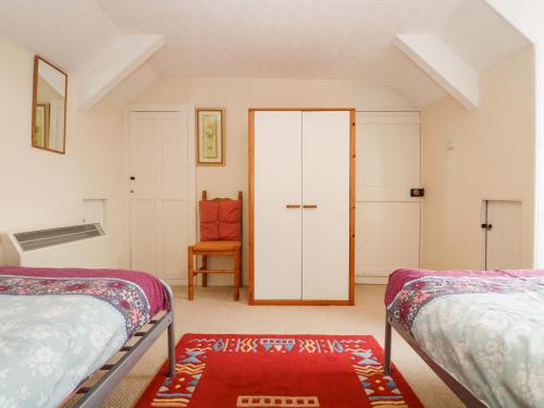 a bedroom with two beds and a red rug at Curlews in Tintagel