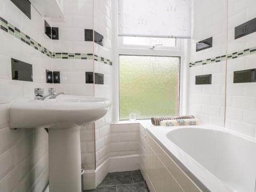 a white bathroom with a sink and a bath tub at Curlews in Tintagel
