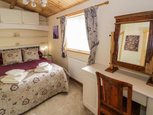 a bedroom with a bed and a mirror and a chair at Brookside Lodge in Worcester