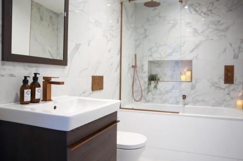 een witte badkamer met een wastafel en een douche bij Berry's Retreat - Kist Accommodates in Knaresborough