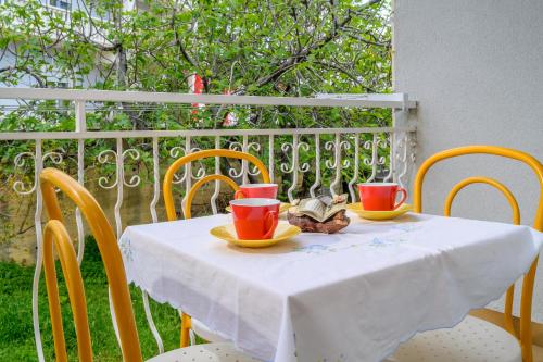 a table with two cups and a plate of food on it at Apartments Jurić in Podstrana