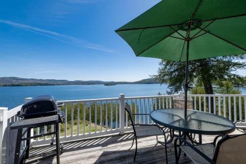 a table and chairs with an umbrella on a deck at Depe Dene Lakeside Resort in Lake George