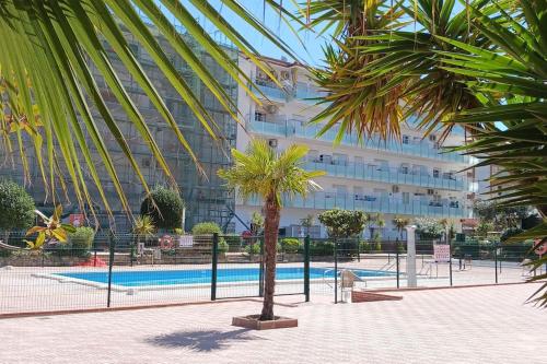 een palmboom voor een groot gebouw bij Alegre apto con piscina, a 300m de la playa. in Blanes