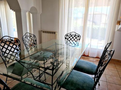une table à manger en verre avec quatre chaises et une fenêtre dans l'établissement Villa avec jardin au calme à 7 min de Cassis, à Roquefort-la-Bédoule