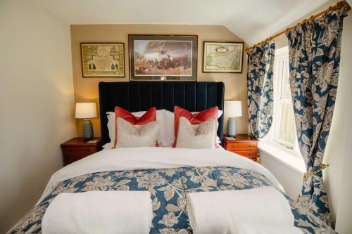 a bedroom with a large bed with red pillows at Thatchers Cottage - Rudge Farm Cottages in Bridport