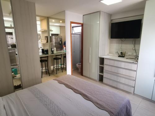 a bedroom with a bed and a kitchen with a sink at Boa Viagem - Charmoso apartamento para casais in Recife