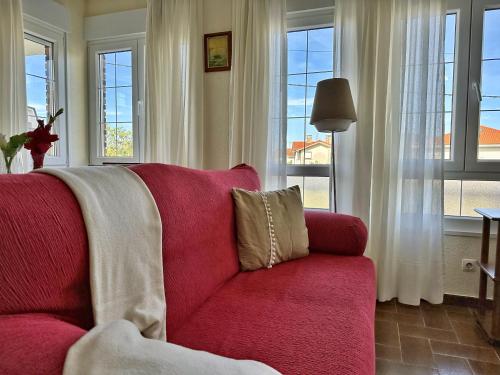 um sofá vermelho numa sala de estar com janelas em Villa Currina - 7801 em Castillo