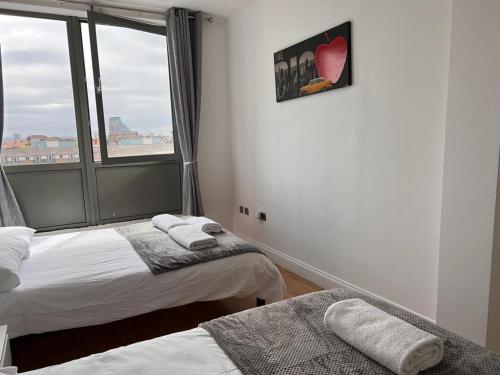 twee bedden in een kamer met een raam bij Cosy Entire Apartment in WhiteChapel/Commercial Rd in Londen