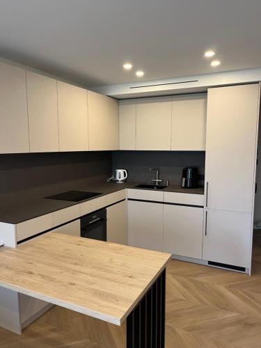 a kitchen with white cabinets and a wooden table at Taikos apartment 57 in Kaunas