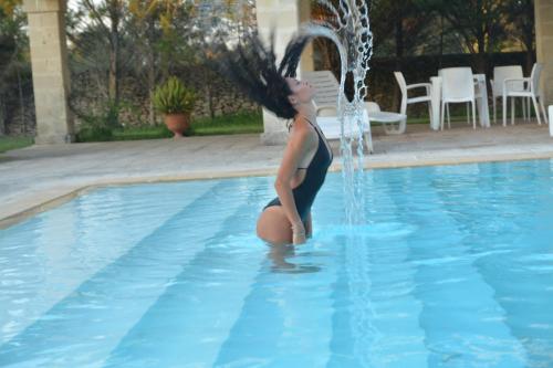 a woman sitting in a swimming pool under a fountain at Tenuta Santicuti in Acaya