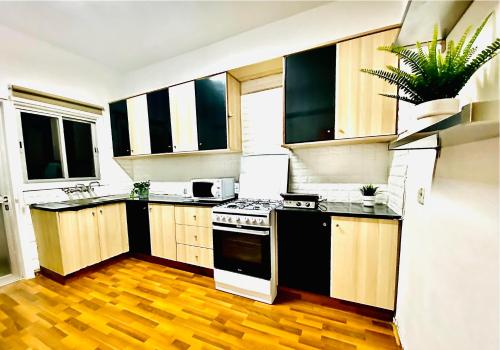 a kitchen with black and white appliances and wooden floors at CHADI APARTMENT in Larnaca