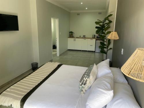 a large white bed in a room with a kitchen at 10 Paul Roos in Kimberley
