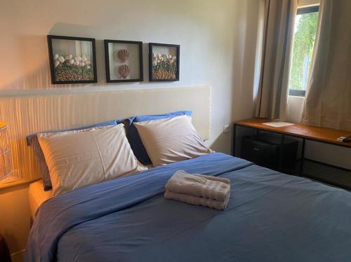 um quarto com uma cama com um cobertor azul e uma janela em Oby Noronha em Fernando de Noronha