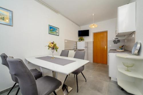 a kitchen and dining room with a white table and chairs at Apartments Jurić in Podstrana
