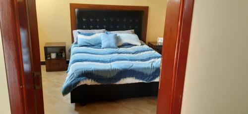 una camera da letto con un grande letto con cuscini blu di MENBi's Apartment a Kitimē