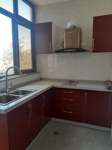 MENBi's Apartment في Kitimē: مطبخ بدولاب بني ومغسلة ونافذة