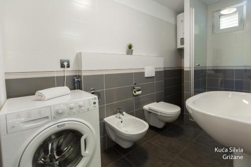 een badkamer met een wasmachine en een wastafel bij House Silvia in Grižane