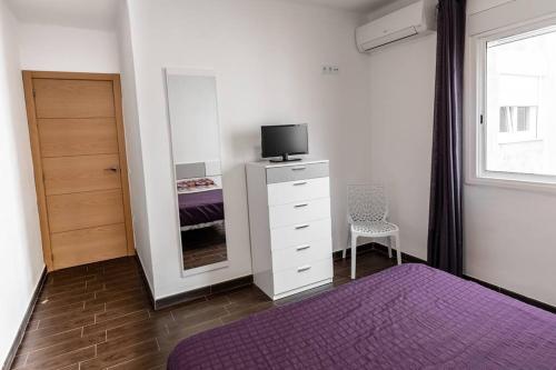 - une chambre avec un lit et une commode avec une télévision dans l'établissement Apartamento céntrico en Peñiscola, à Peñíscola