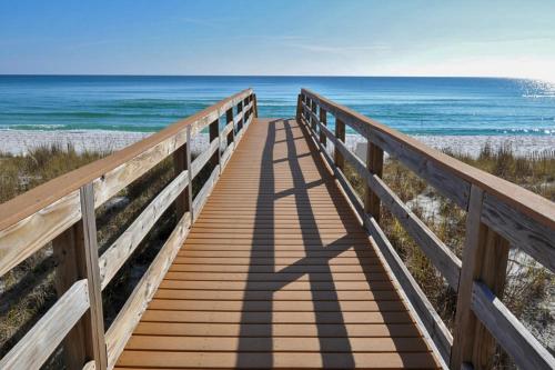un paseo marítimo de madera que conduce a la playa en Portofino Island Resort & Spa 1-1402, en Pensacola Beach