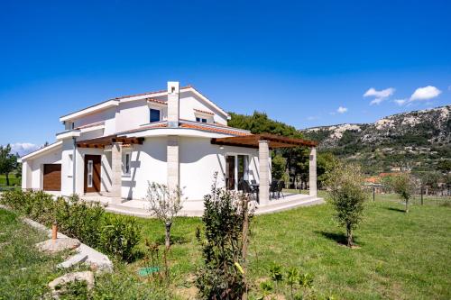 a white house in a field with mountains in the background at Villa Calma in Rab