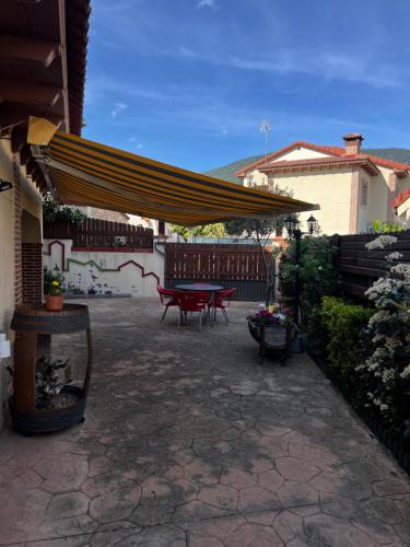 a patio with a table and a yellow umbrella at Casa Rural La Chistera in Avila