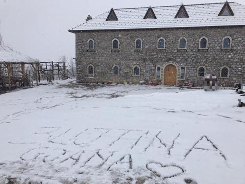 a stone building with the word asylum written in the snow at Bujtina Gjana in Kukës
