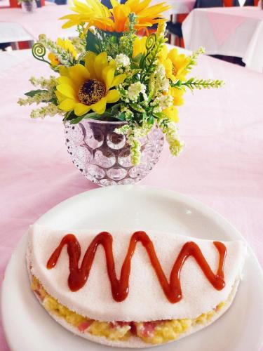 einen Kuchen auf einem Teller auf einem Tisch mit einer Vase Blumen in der Unterkunft Marsallis Praia JR 406 in Natal