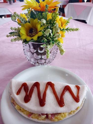 ein Stück Kuchen auf einem Teller mit einer Blumenvase in der Unterkunft Marsallis Praia JR 406 in Natal