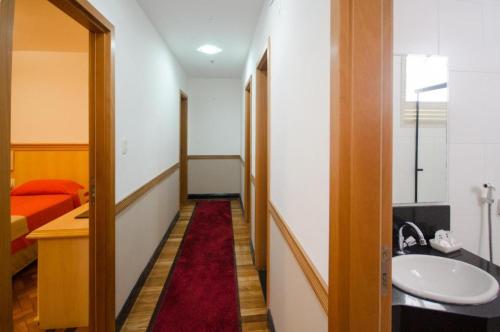 a hallway with a bathroom with a sink and a bed at Hotel Monte Alegre in Rio de Janeiro