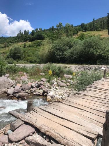 a wooden bridge over a river with rocks at Bujtina Gjana in Kukës