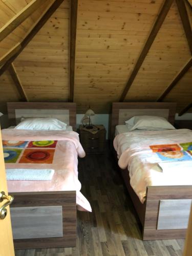 two beds in a room with wooden ceilings at Bujtina Gjana in Kukës