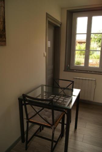 a glass table and a chair in a room at La longère de Suzanne in Arrest