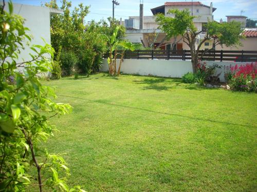 a yard with green grass and a white wall at Marina's House in Paralía Avlídhos