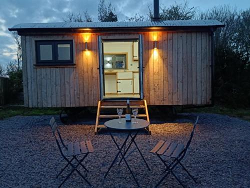 een kleine hut met een tafel en stoelen ervoor bij Old Quay Escape in Tenby