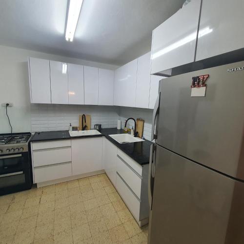 a kitchen with white cabinets and a stainless steel refrigerator at צפת שלי in Safed