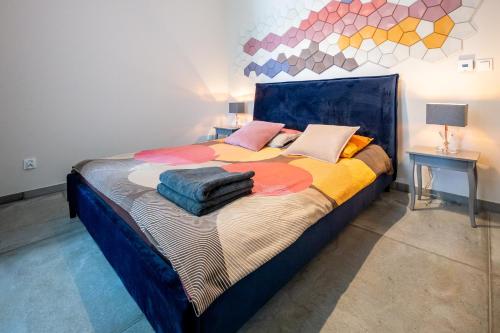 ein Schlafzimmer mit einem großen Bett mit bunter Bettwäsche und Kissen in der Unterkunft Apartament Zakatek z ogrodkiem i miejscem w garazu podziemnym in Bielsko-Biała