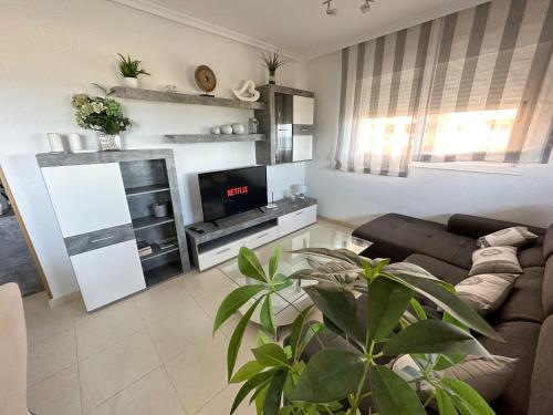 a living room with a couch and a tv at Apartamentos Be Suites Primera Linea in Oropesa del Mar