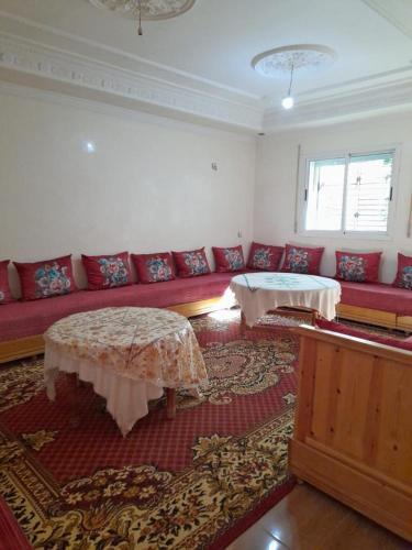 ein Wohnzimmer mit einem roten Sofa und Tischen in der Unterkunft شقة ازرو لللكراء in Azrou