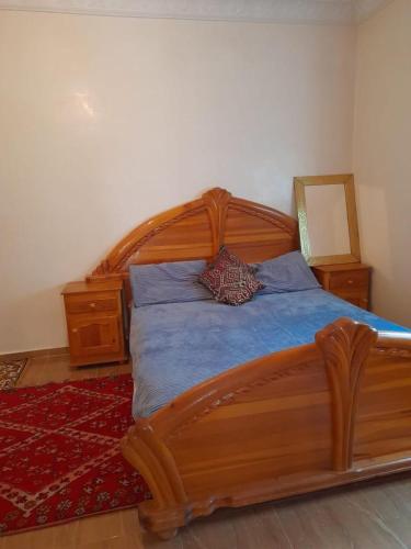 Schlafzimmer mit einem Holzbett und einem roten Teppich in der Unterkunft شقة ازرو لللكراء in Azrou