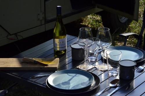 una mesa con platos y copas y una botella de vino en DEFCAMP, en Rixensart