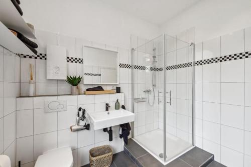 a white bathroom with a sink and a shower at Wuppertaler Altbau-Traum Gutenberg in Wuppertal