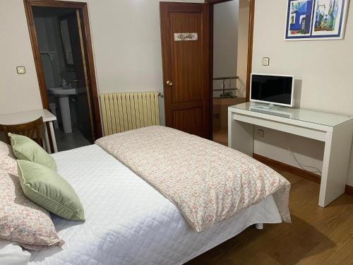 a bedroom with a bed and a desk with a computer at Hostería El Cruce in Cabezón de la Sal