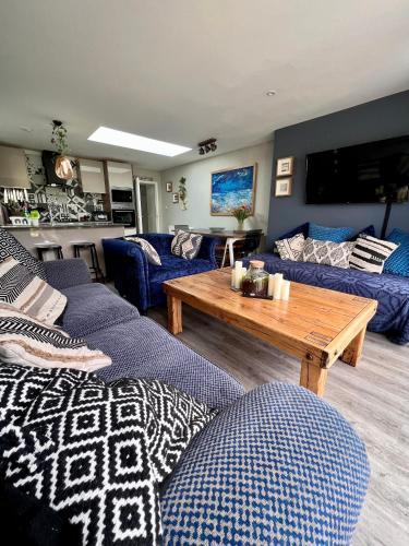 a living room with blue couches and a wooden table at Sandy feet retreat in Exmouth