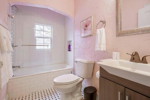 a bathroom with a toilet and a tub and a sink at Pastel Palace - near Plaza & Uptown 23rd in Oklahoma City