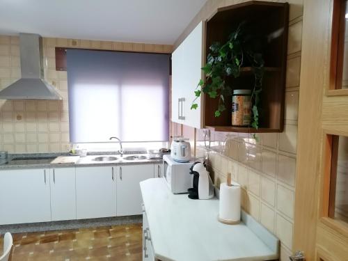 a kitchen with white cabinets and a sink and a counter at Lar de Yago - Casa in Barreiros