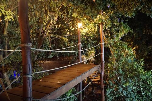 eine hölzerne Hängebrücke mit Licht darauf in der Unterkunft La Playita in Guachaca