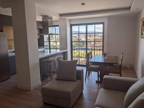 a living room with a couch and a table and a kitchen at Stunning 5th floor condo w/ scenic view near tran in Cuenca